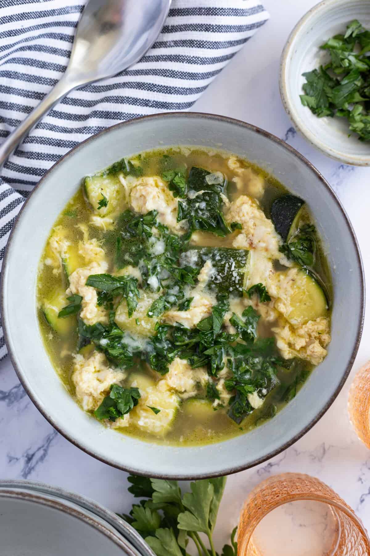 A bowl of chopped zucchini in vegetable broth with scrambled eggs.