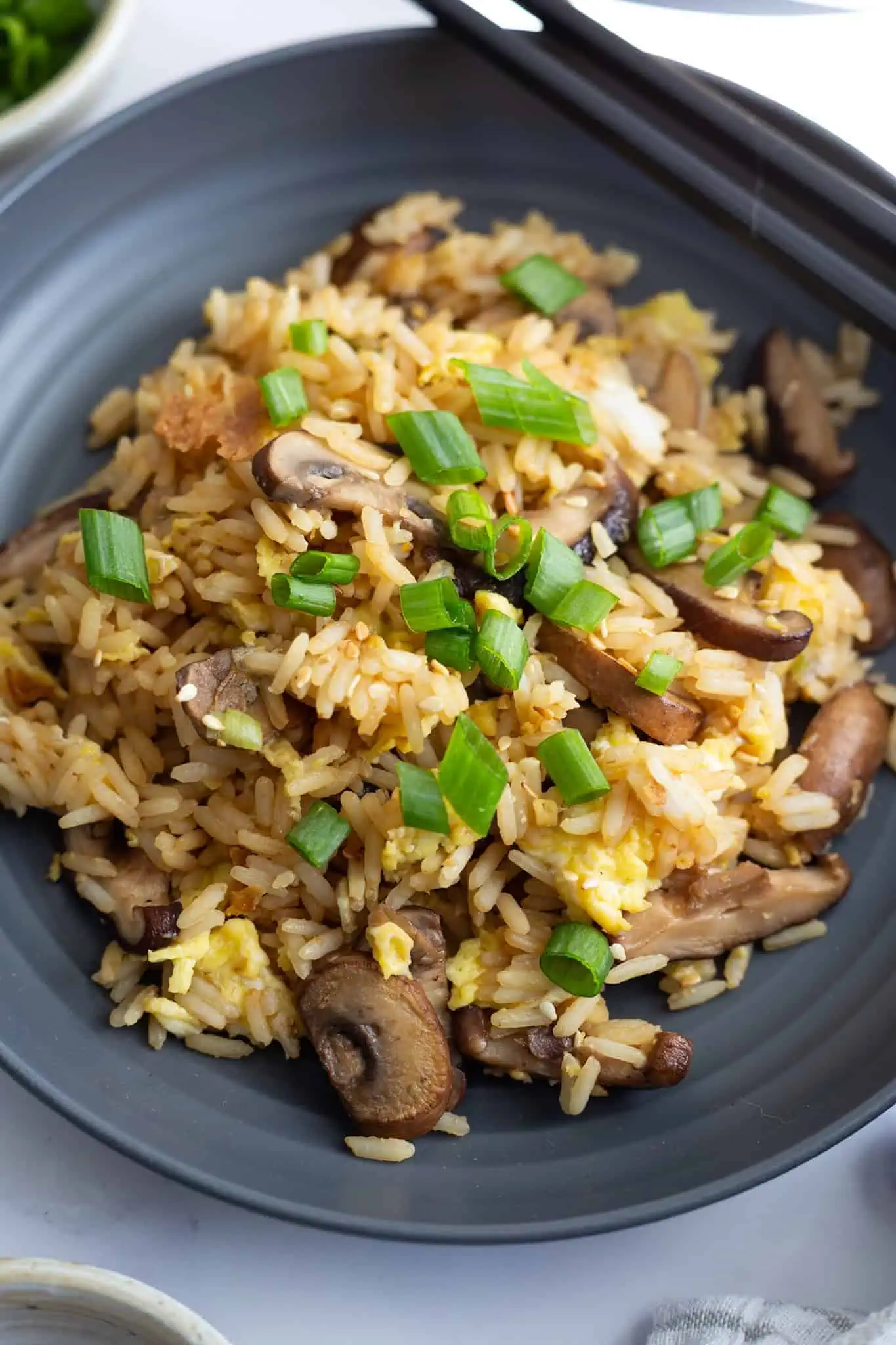 A grey plate topped with miso fried rice, cooked with cremini and shiitake mushrooms.