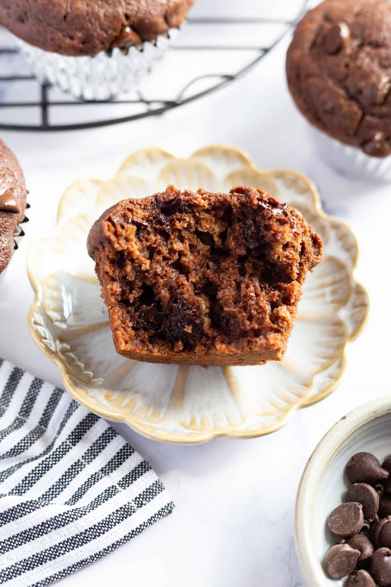 A sliced chocolate chip muffin with the interior exposed, on a serving plate.