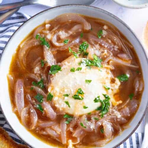 A bowl of Tuscan onion soup with poached egg, garnished with minced parsley.