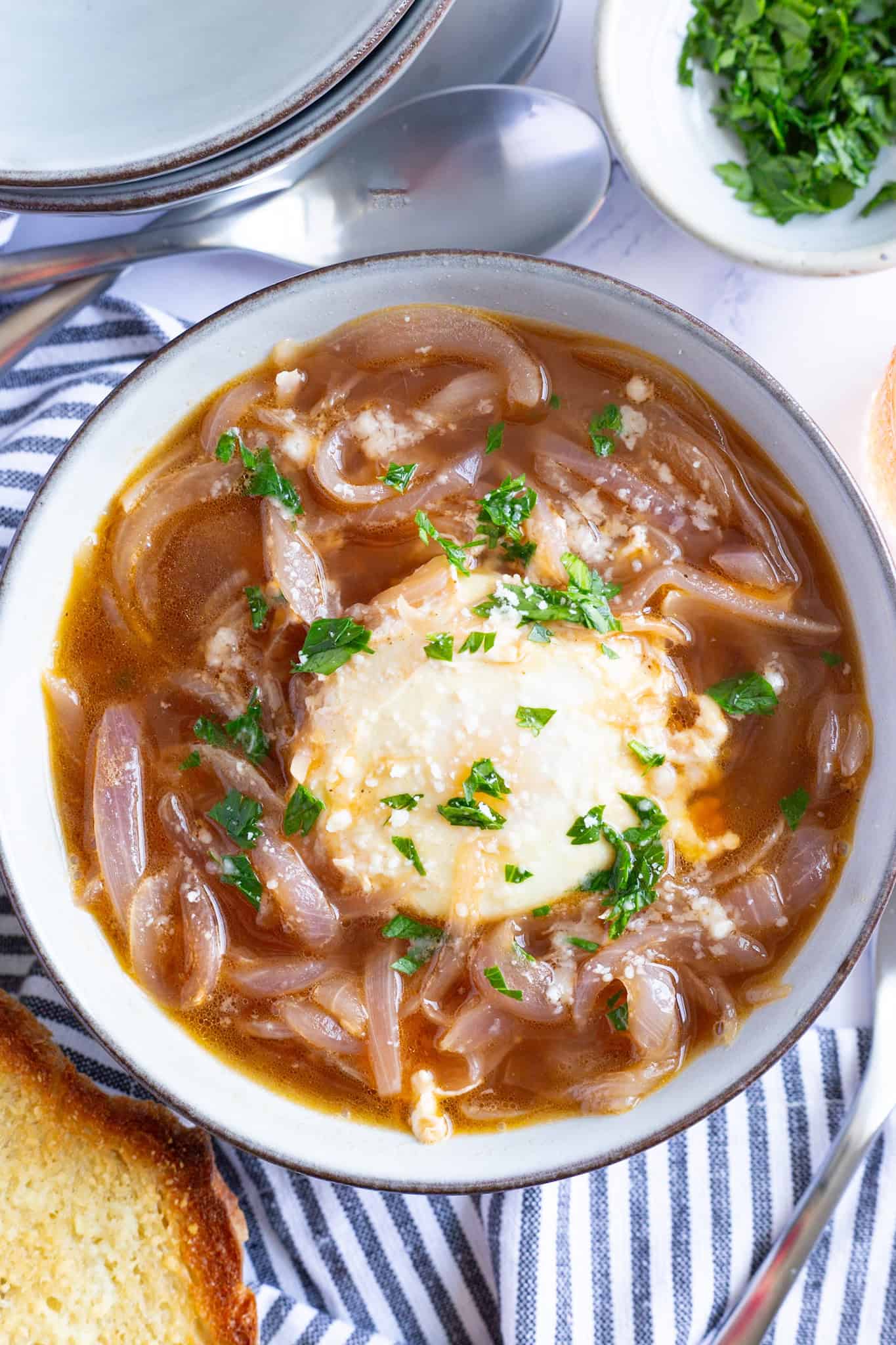A bowl of Tuscan onion soup with poached egg, garnished with minced parsley.