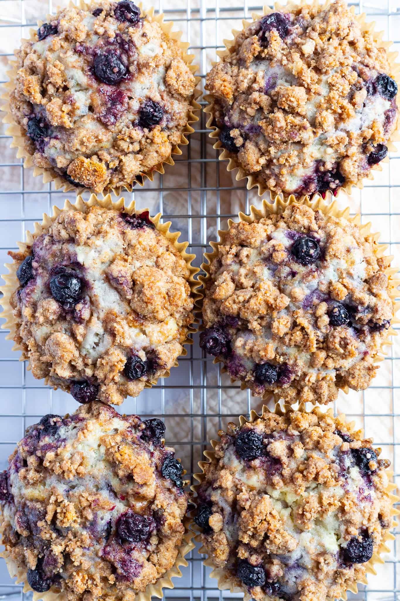Blueberry streusel muffins cooling on a baking rack.