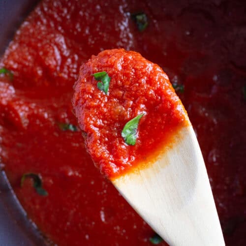 A wooden spoon filled with easy tomato basil pasta sauce.