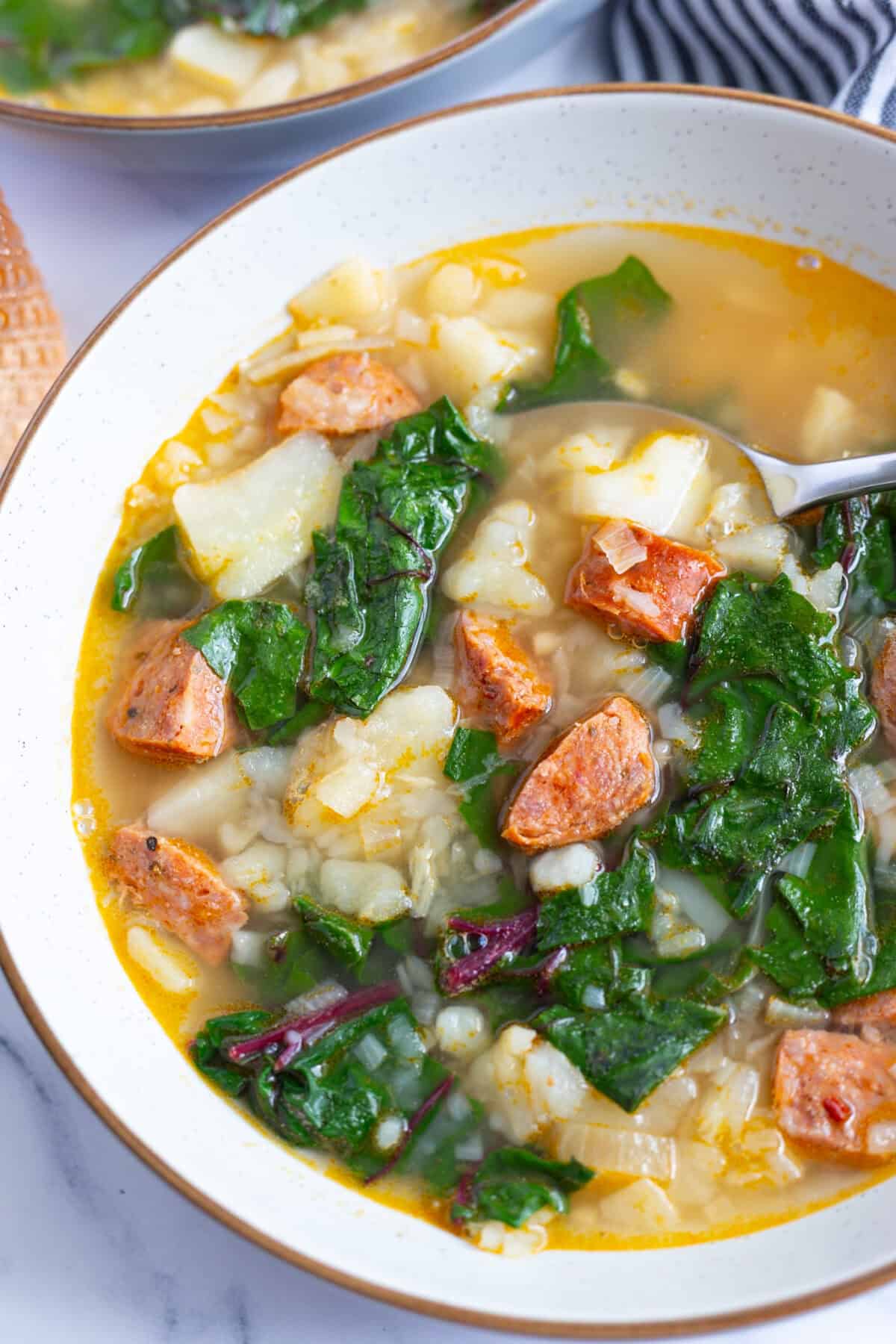 A bowl of chorizo potato soup with Swiss chard.