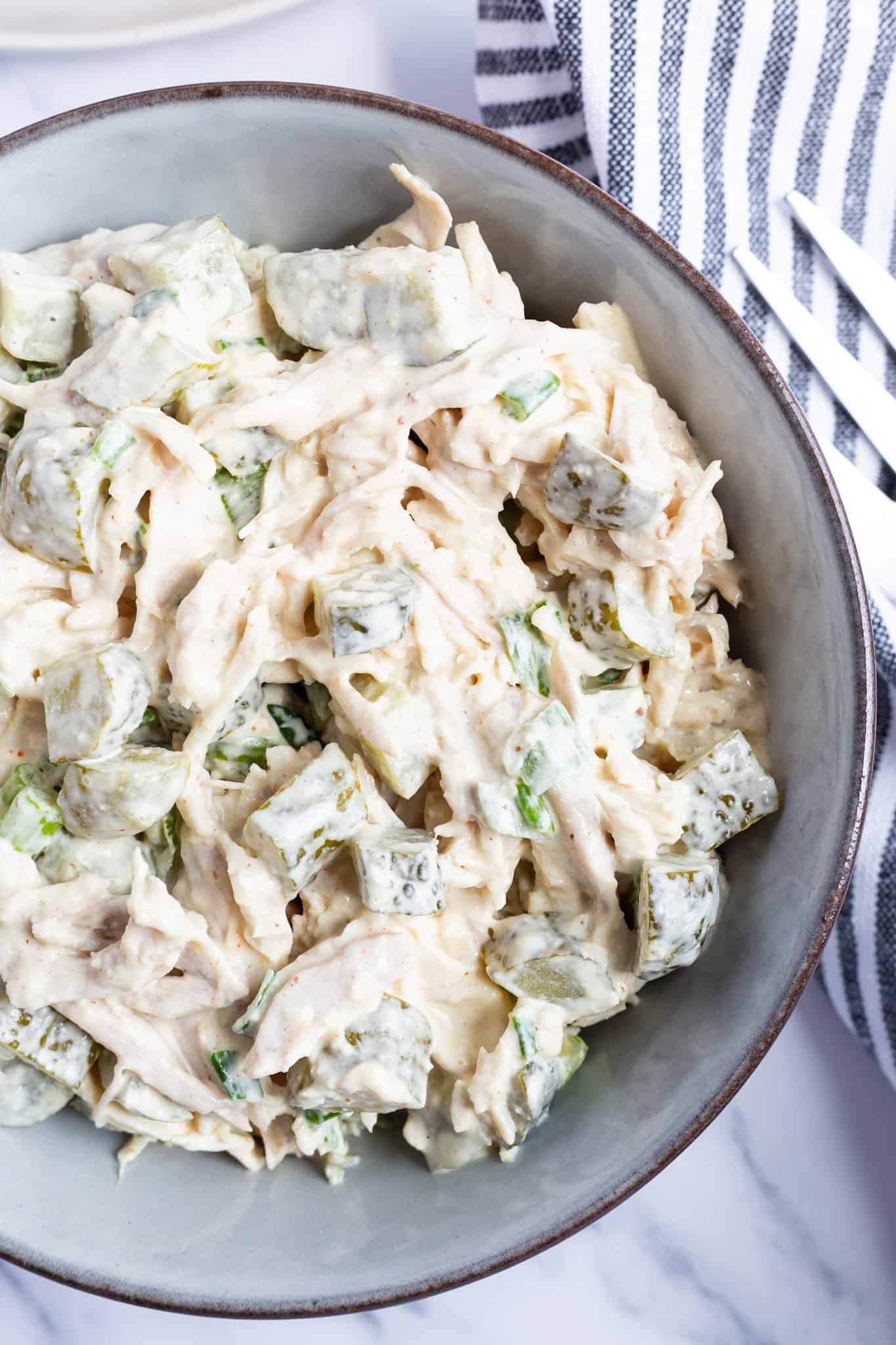 A bowl of creamy dill pickle chicken salad with lots of pickles.