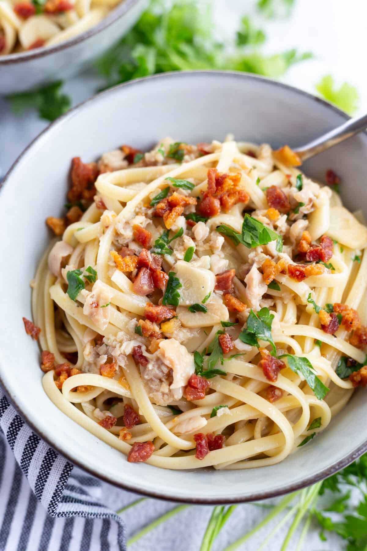 A bowl of pasta made with pancetta and canned clams.