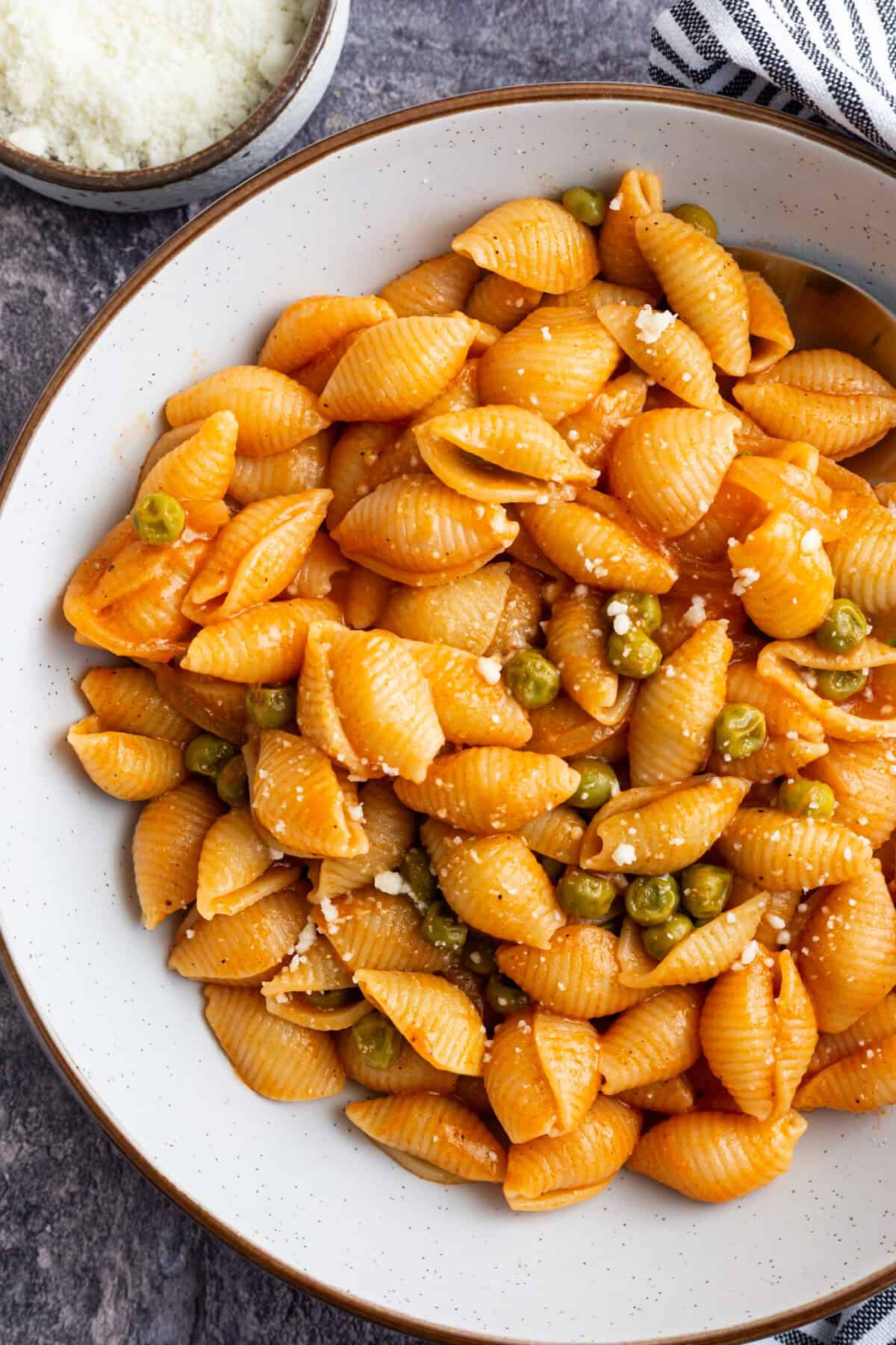 Macaroni and peas in red sauce, garnished with Pecorino.