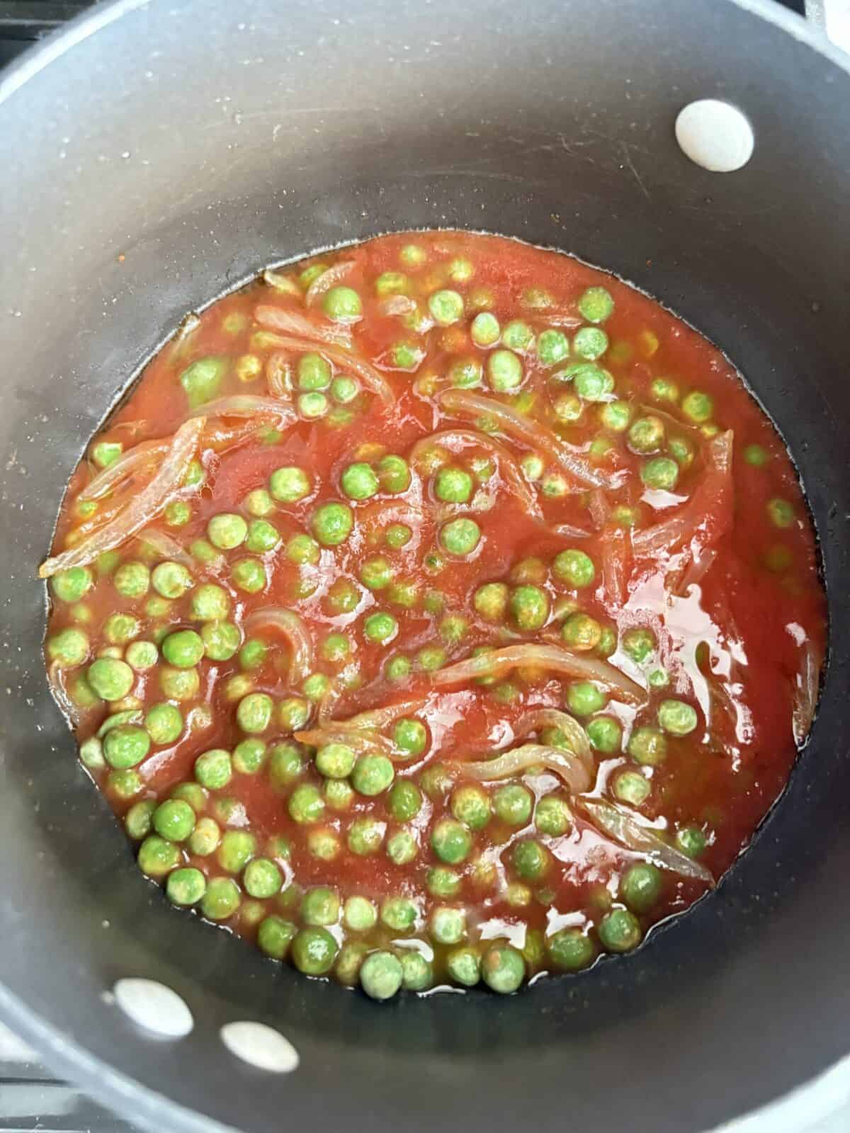 A pot of simmered tomato sauce and peas.