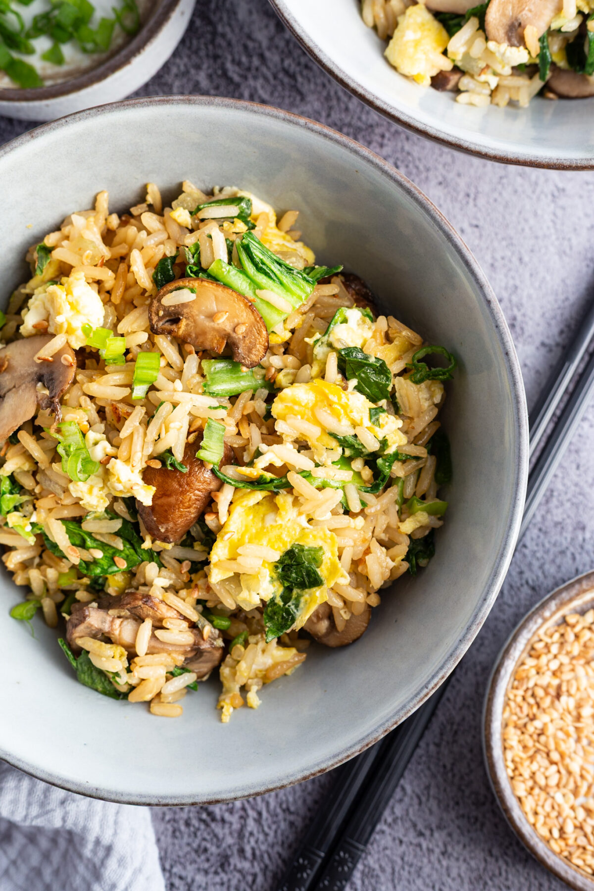 A bowl of bok choy fried rice with chopsticks on the side.