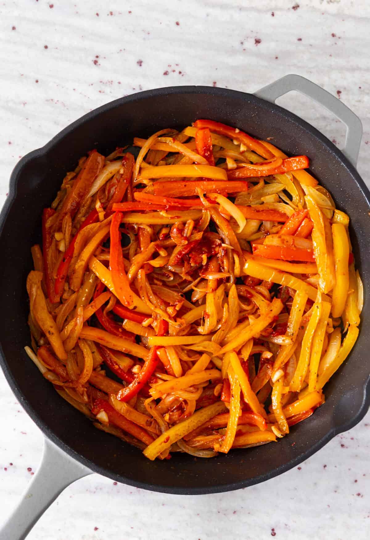 A pan of cooked peppers and onions with tomato paste.