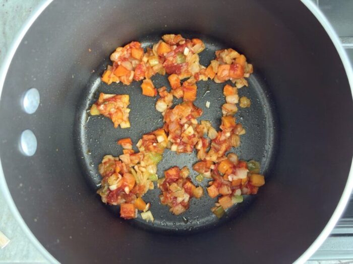 A pot with cooked tomato paste and mirepoix.