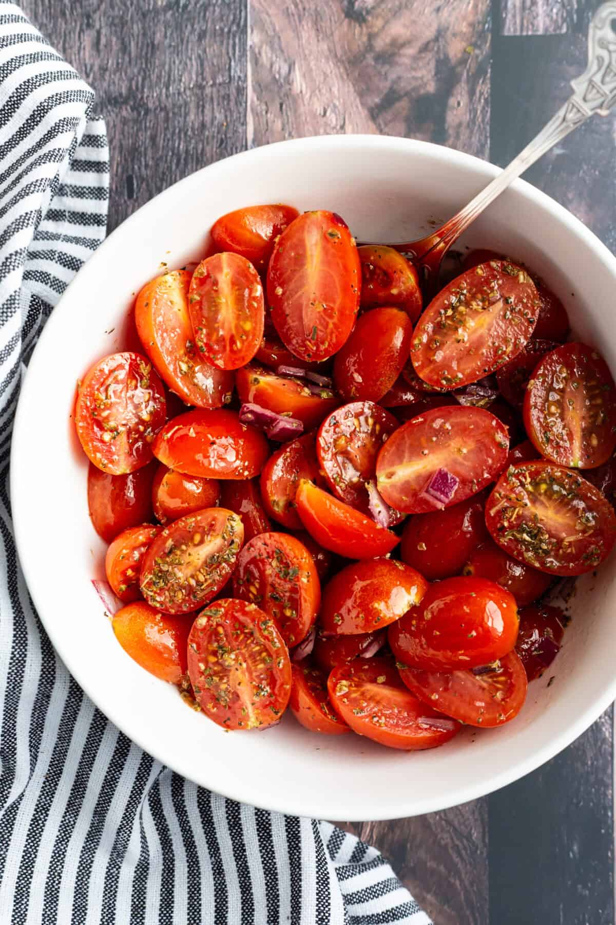 A bowl of cherry tomatoes tossed in oil and vinegar.
