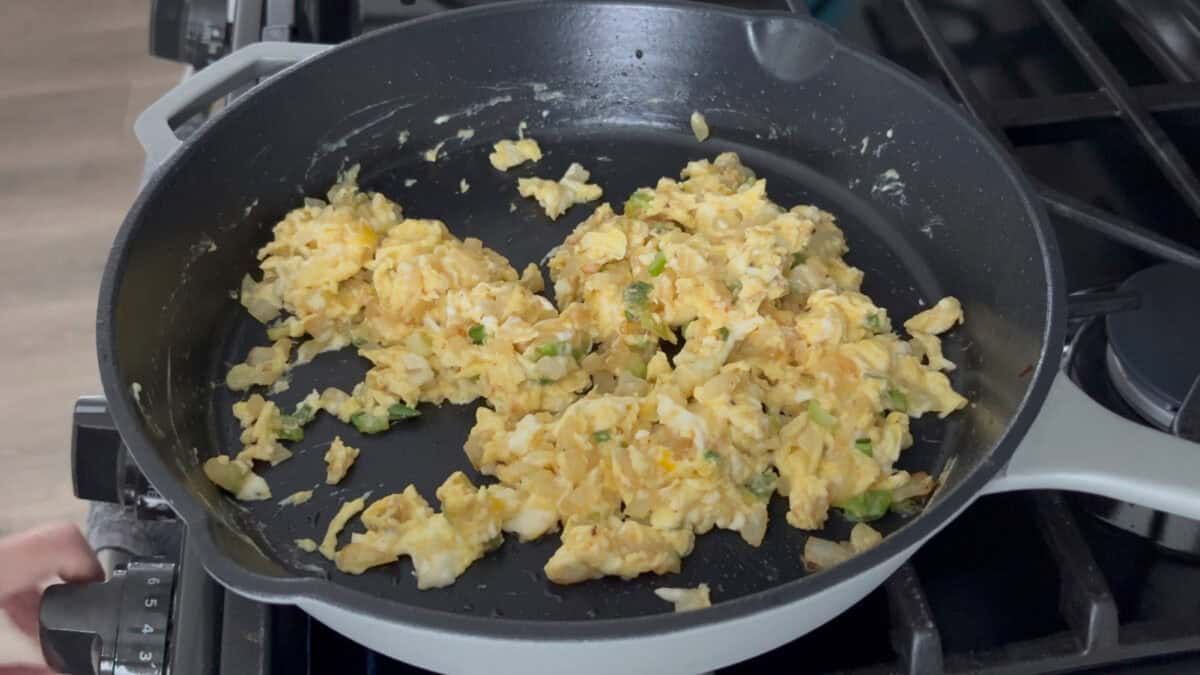 A pan of scrambled eggs with scallions.