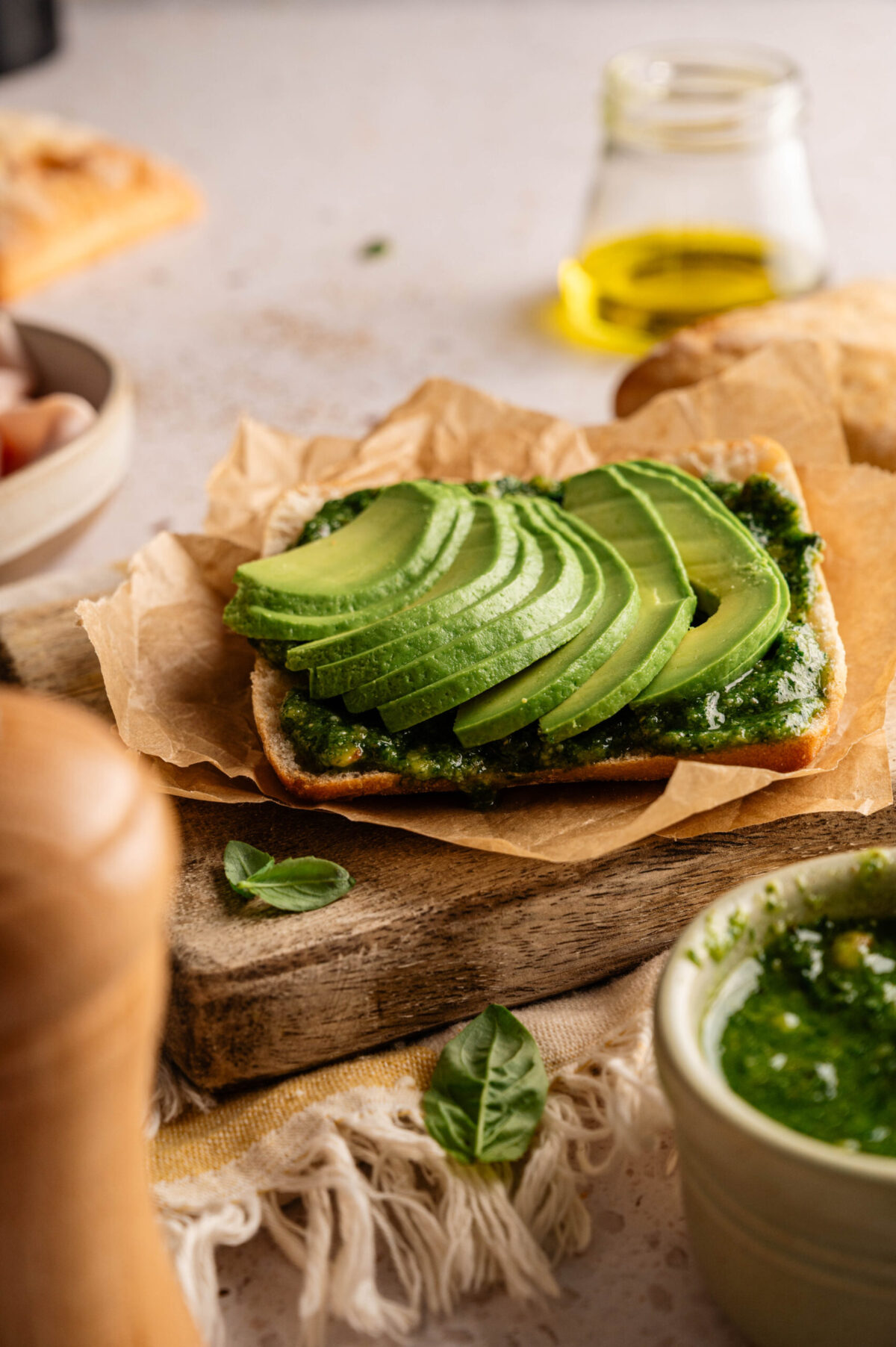 The partial making of a sandwich showing pesto and avocado.