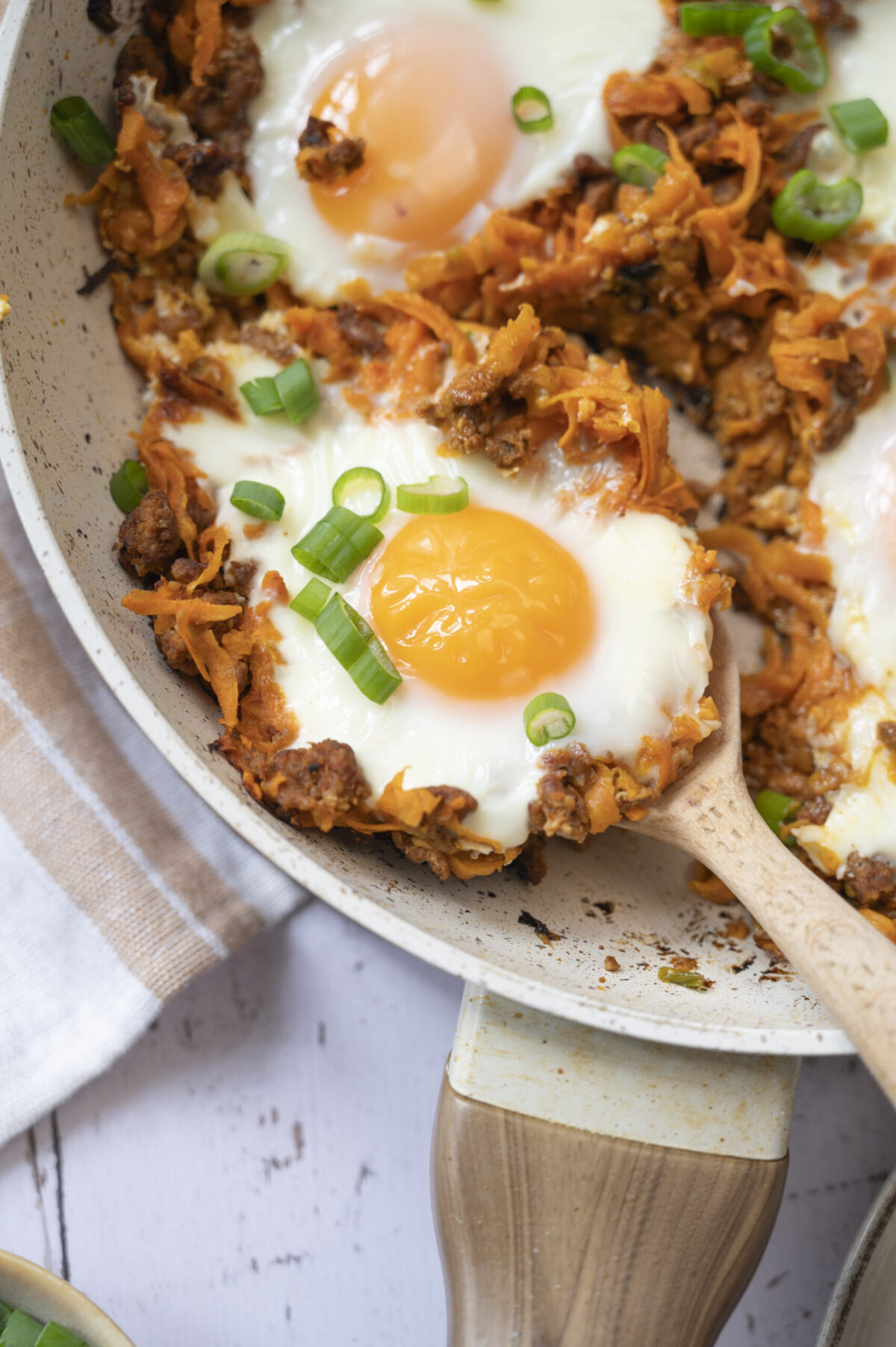 Baked eggs with chorizo and sweet potato, topped with scallions.