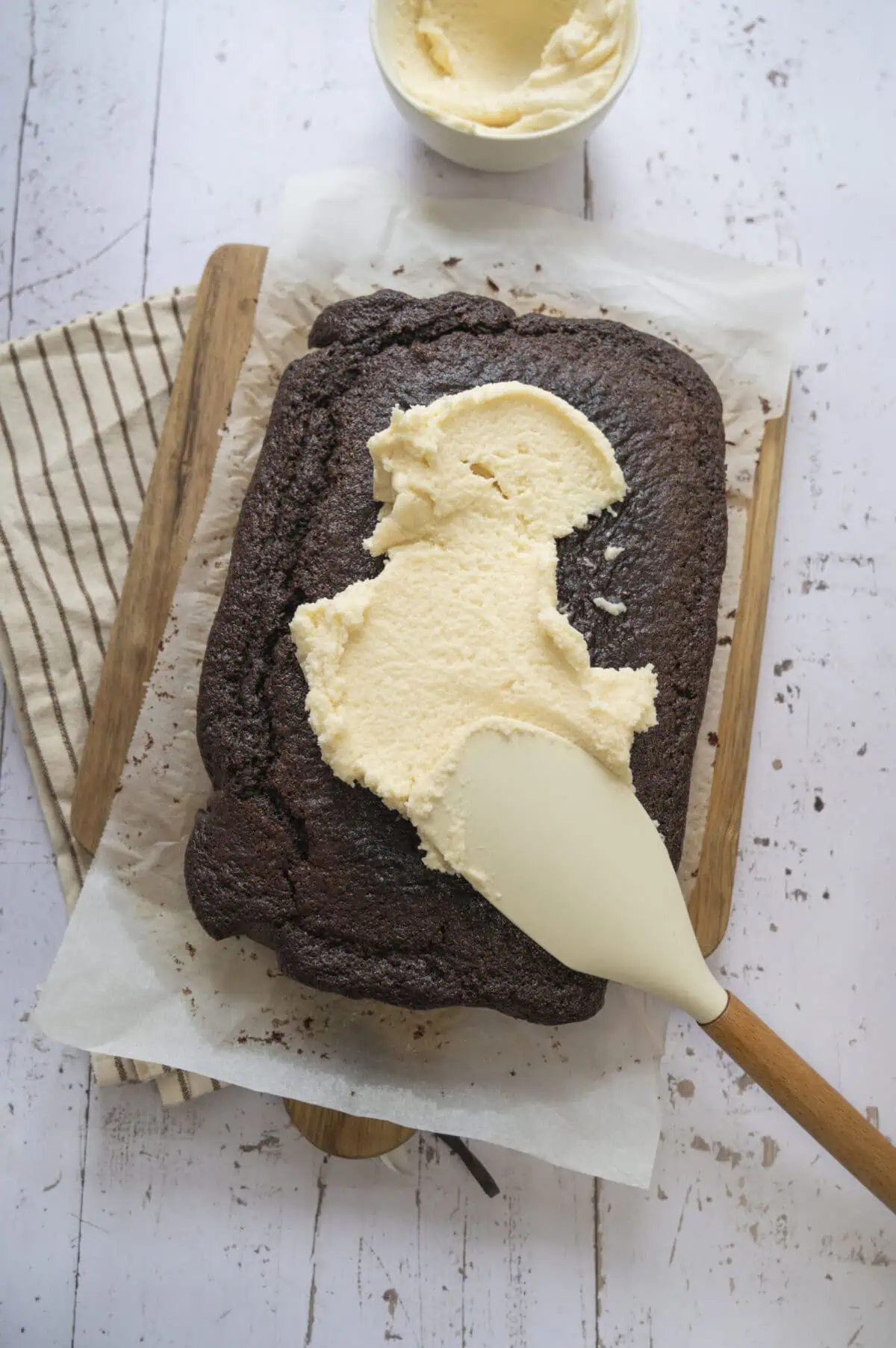 A chocolate cake being frosted.