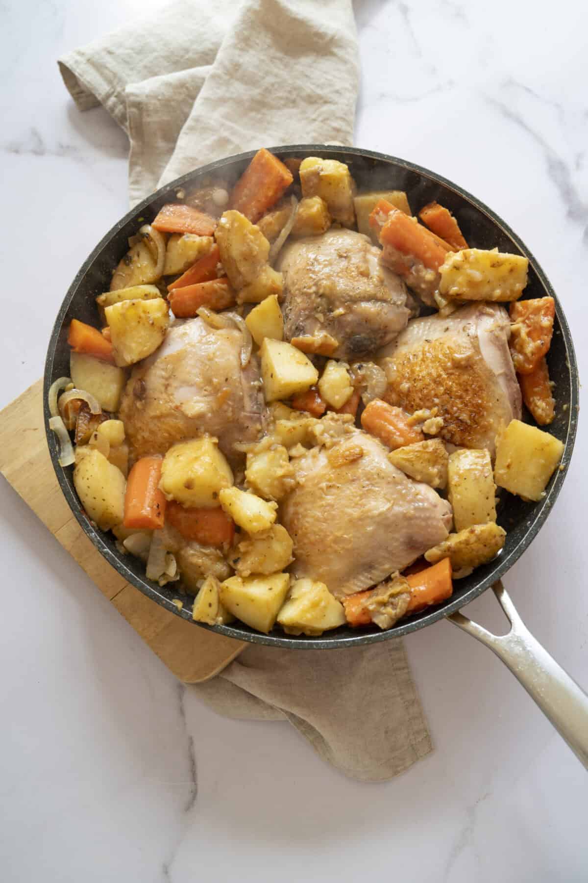 A pan of chicken with potatoes and carrots.