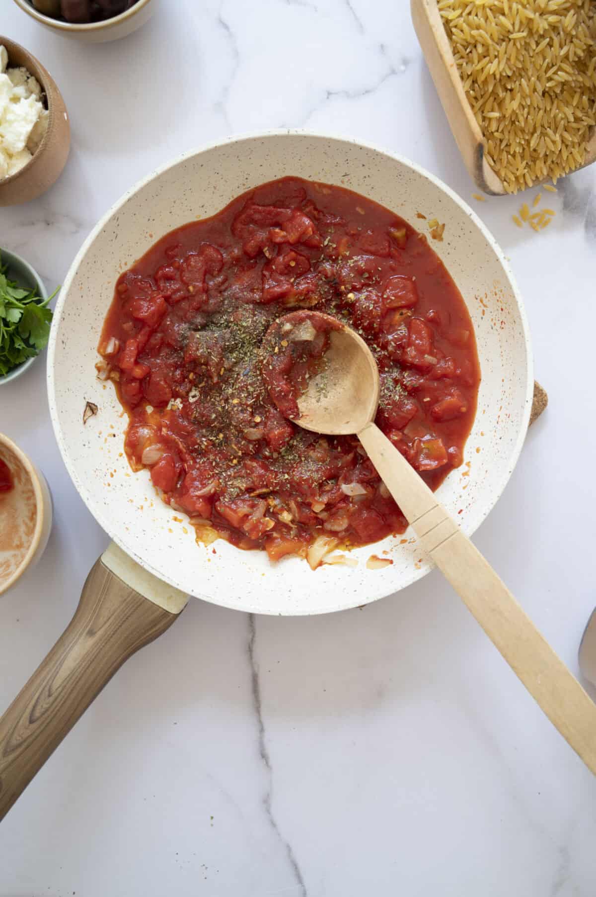 A pan of cooked diced tomatoes and herbs.