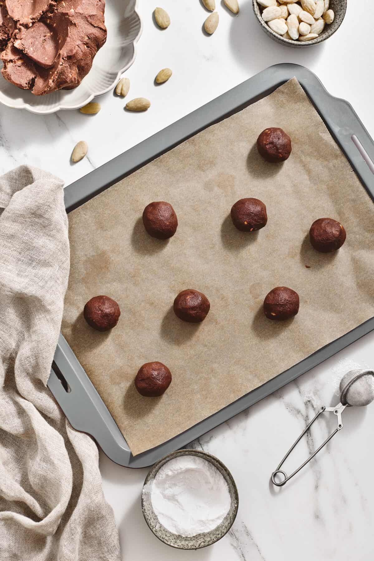 Balls of raw cookie dough on a baking sheet.