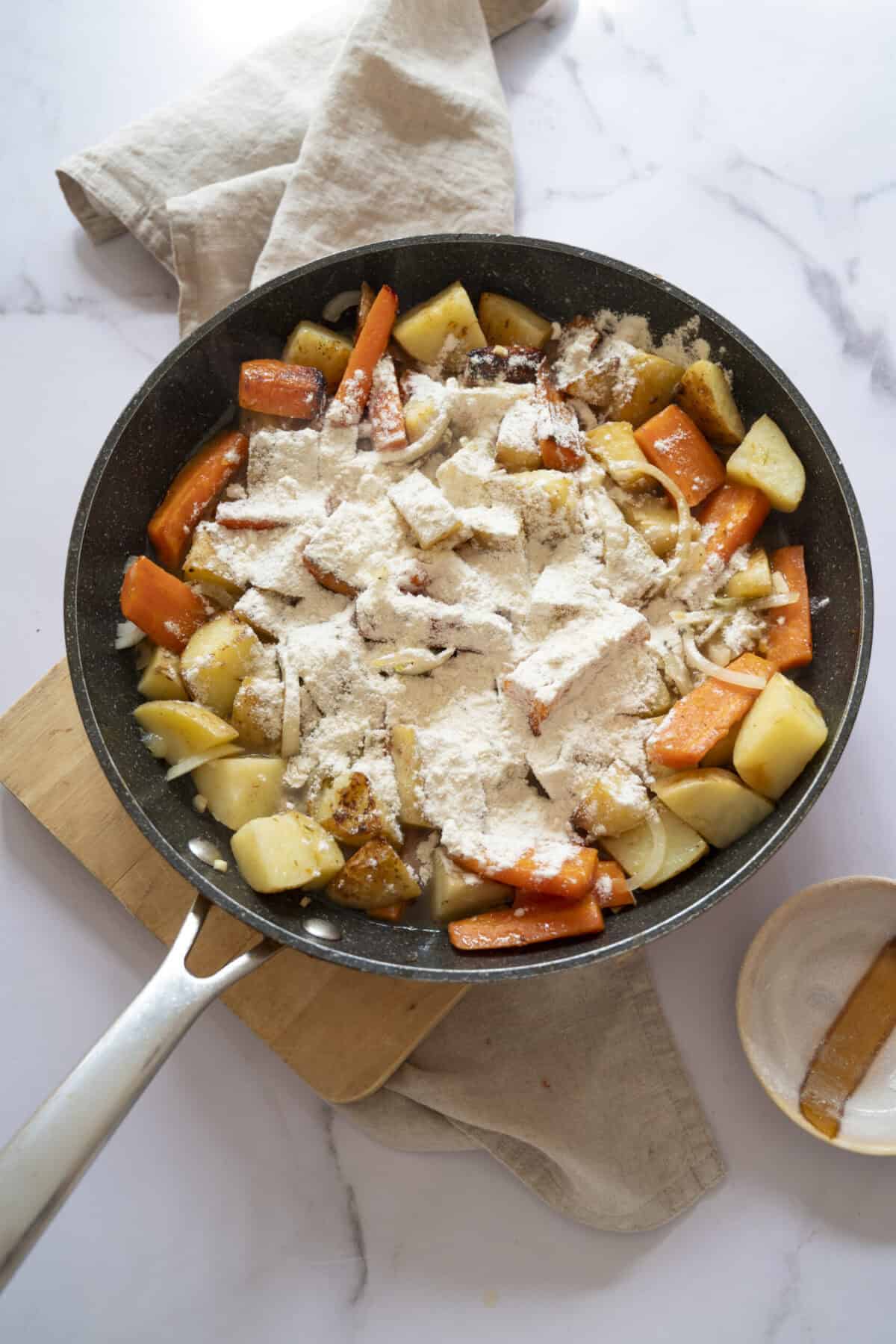 A pan of potatoes and carrots with flour for thickening.