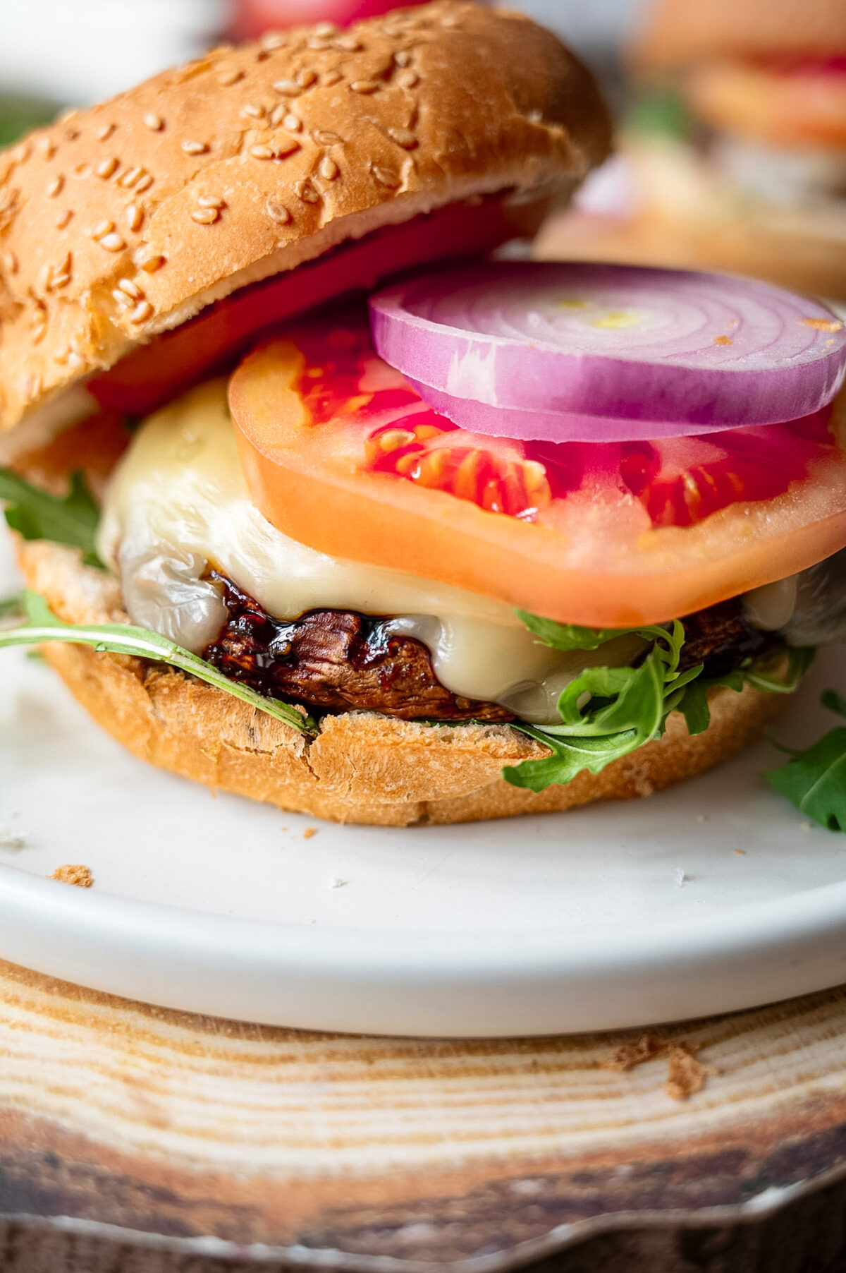 A portobello mushroom burger topped with cheese, tomato, and red onion.