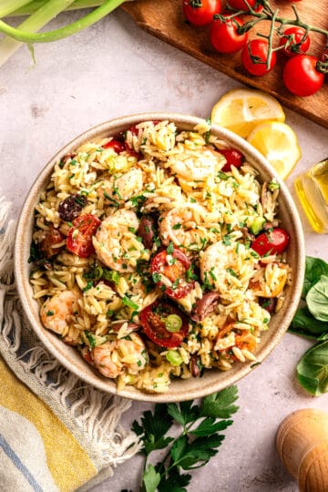 A big bowl of shrimp orzo salad with olives and feta.