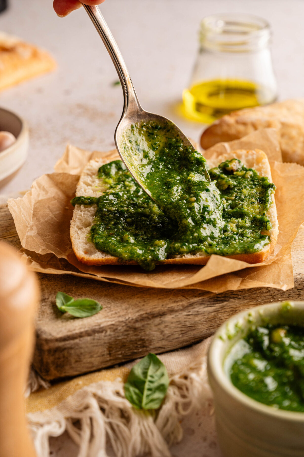 Pesto smeared onto a bottom piece of ciabatta bread.
