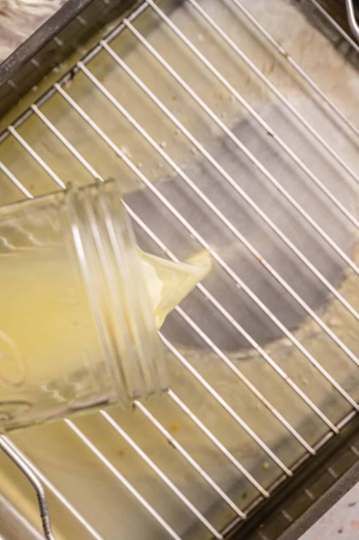 Chicken broth being poured into a roasted pan.
