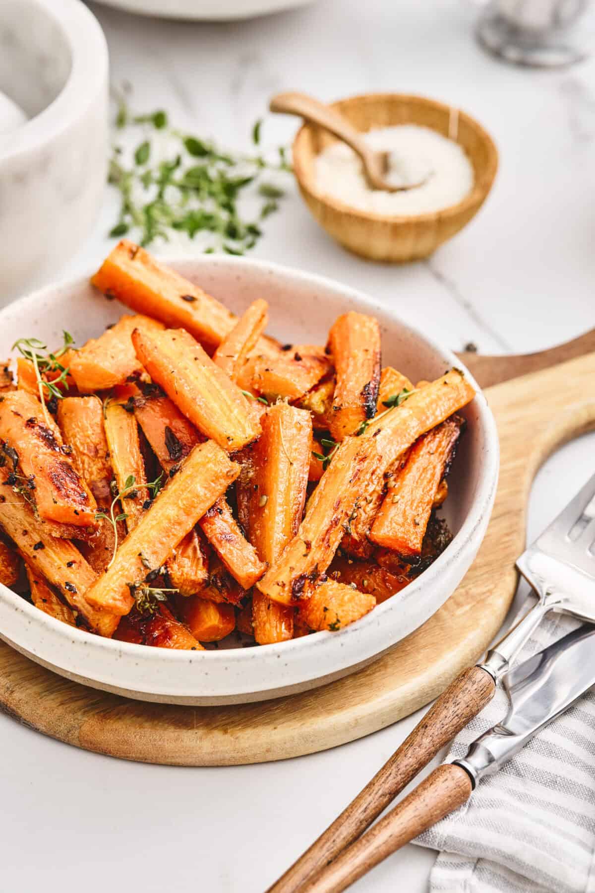 A bowl of roasted parmesan carrots with thyme.
