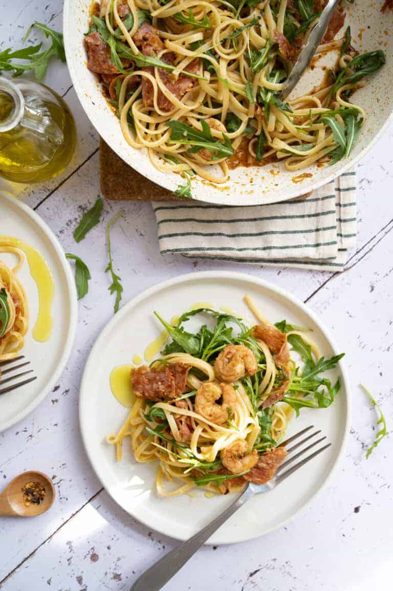 Plates of shrimp and chorizo pasta with arugula.