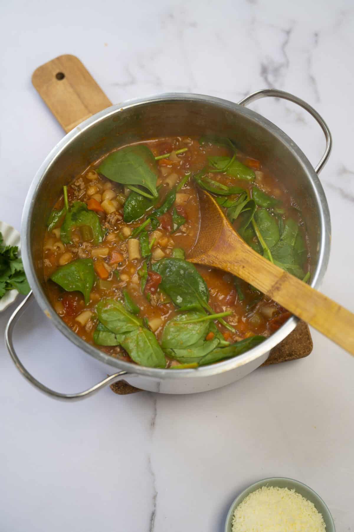 A pot of pasta fazool with spinach.