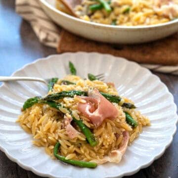 A plate of asparagus orzo with prosciutto.