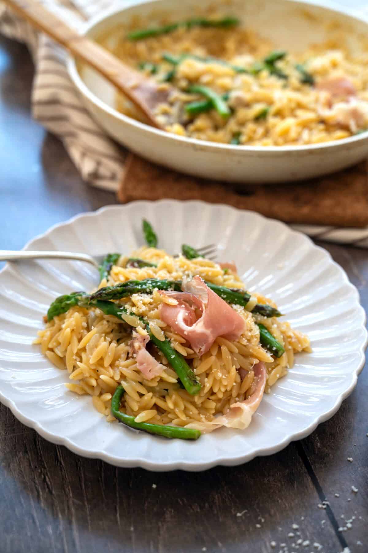 A plate of asparagus orzo with prosciutto.
