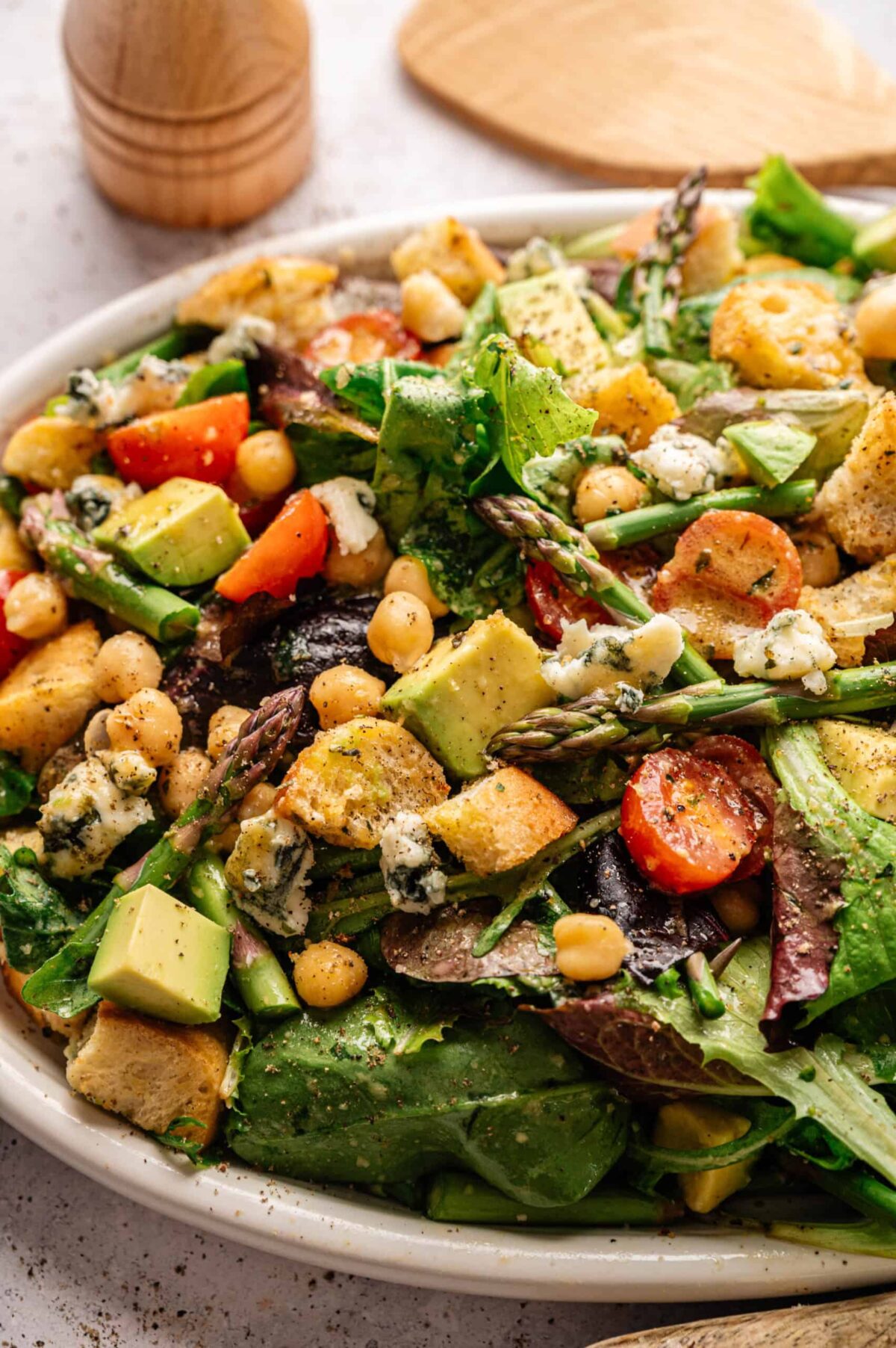 A salad topped with blue cheese, asparagus tips, cherry tomatoes, and croutons.