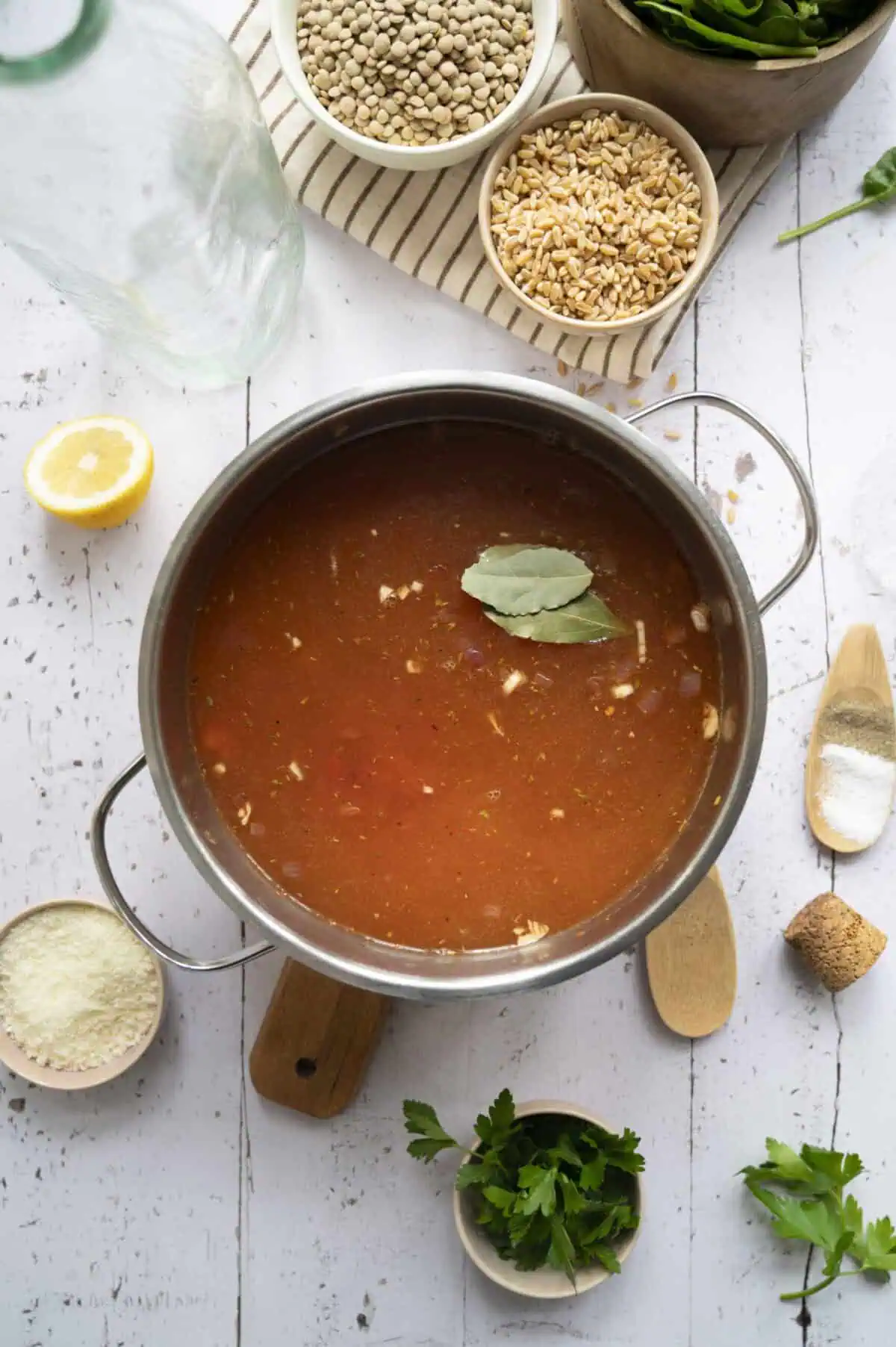 A pot of soup filled with chicken broth, lentils, and barley.