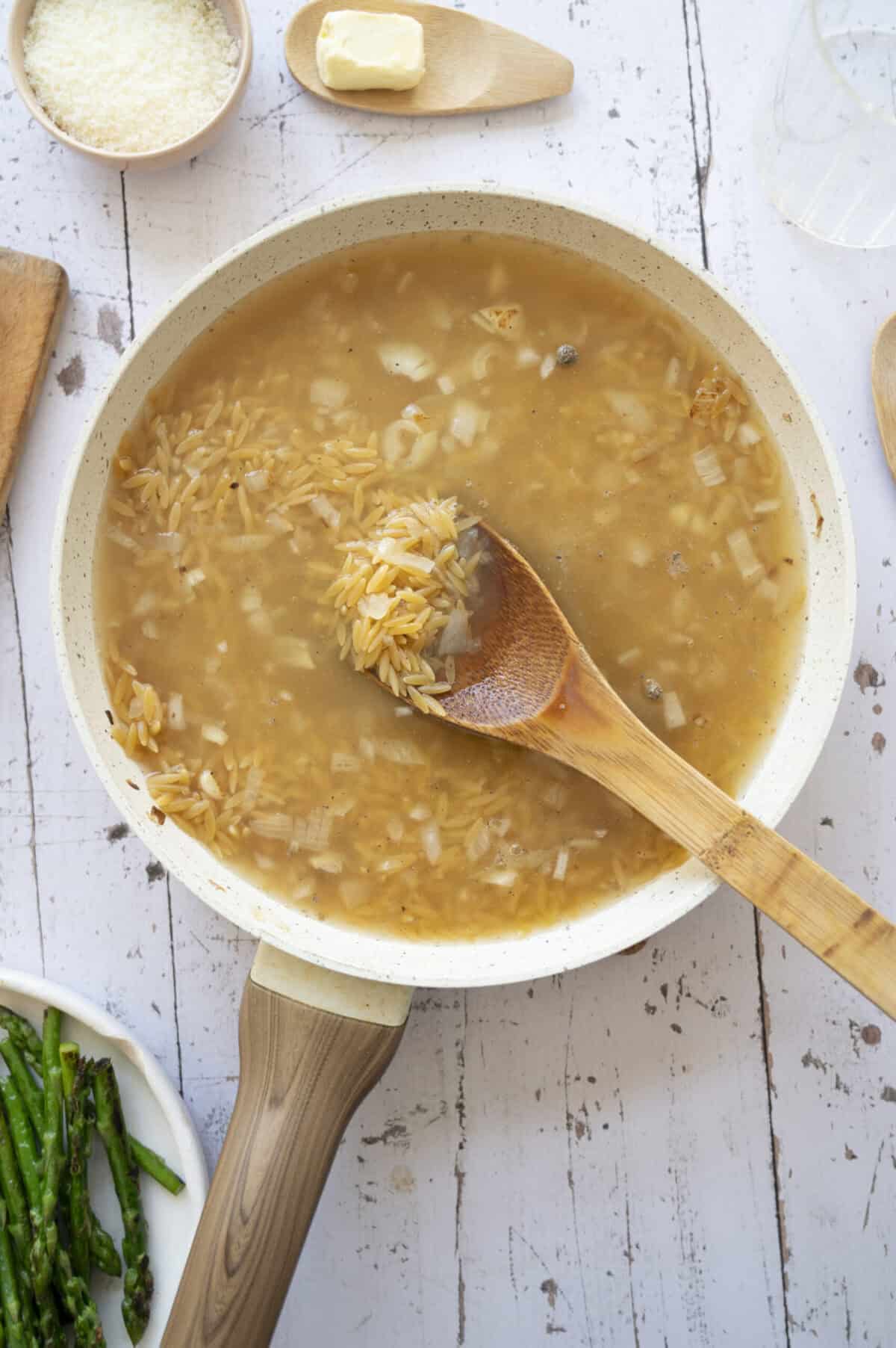 A pan of orzo cooking in broth.