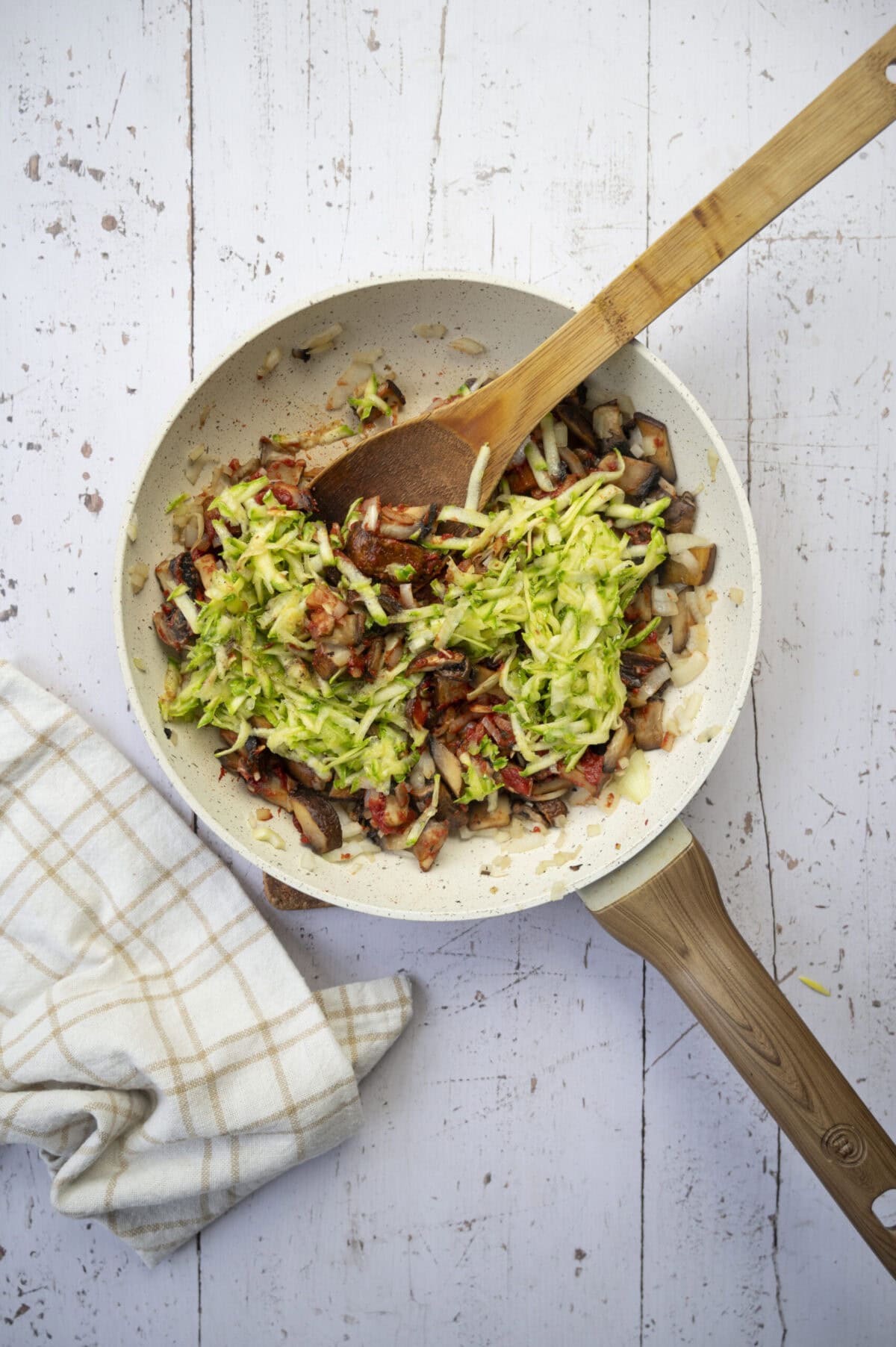 A pan of cooked mushrooms and grated zucchini.