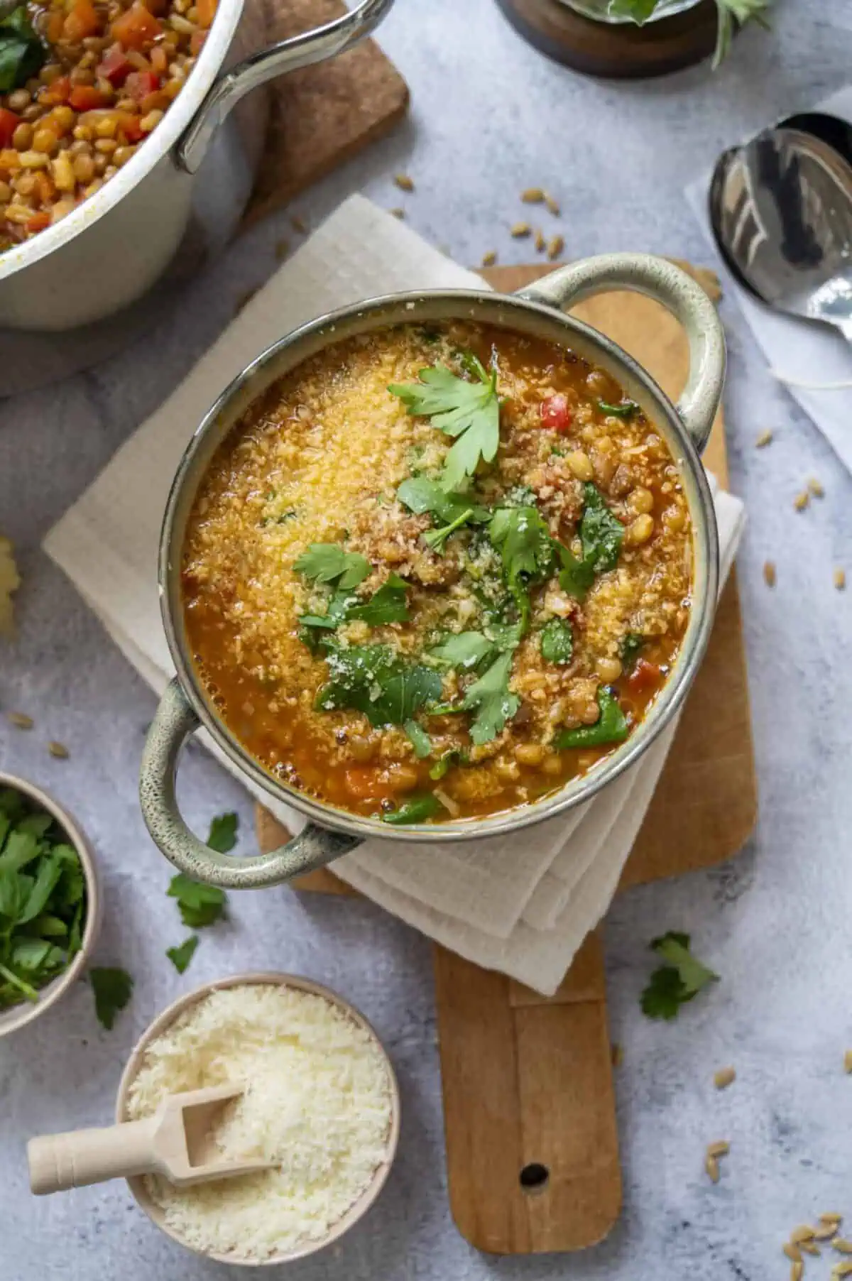 A bowl of lentil and barley soup garnished with parsley and Pecorino.