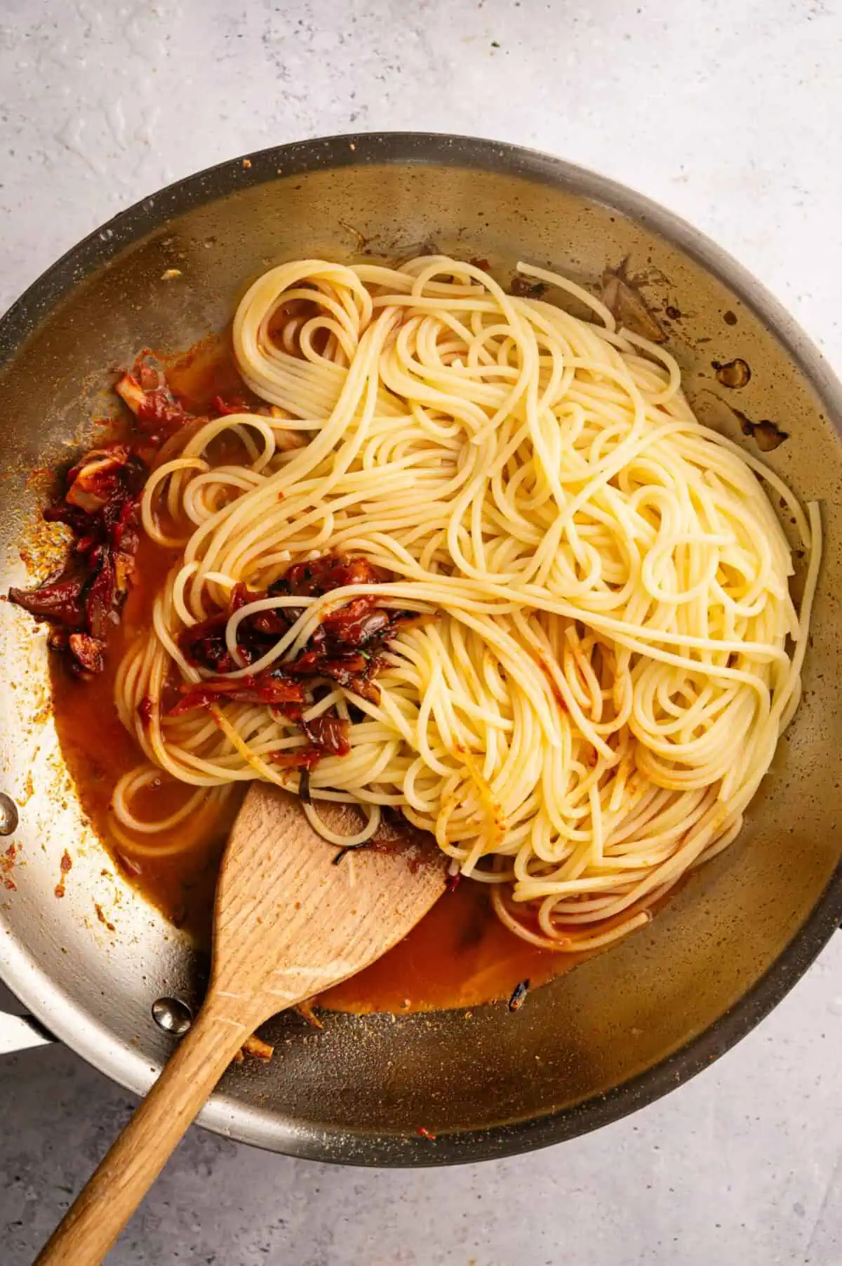 A pan of spaghetti tossed with caramelized shallots.