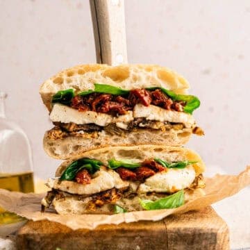 A stacked roasted eggplant sandwich with eggplant, mozzarella, sun-dried tomatoes, and fresh basil.
