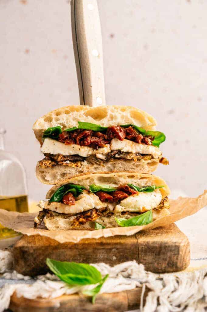 A stacked roasted eggplant sandwich with eggplant, mozzarella, sun-dried tomatoes, and fresh basil.
