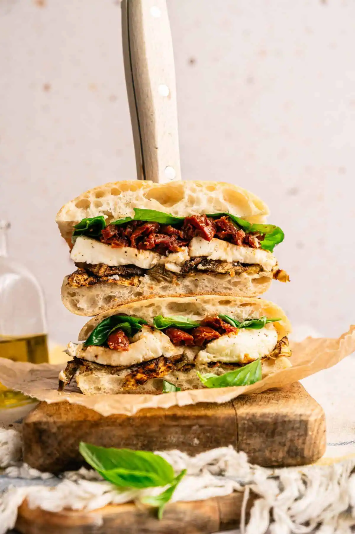 A stacked roasted eggplant sandwich with eggplant, mozzarella, sun-dried tomatoes, and fresh basil.