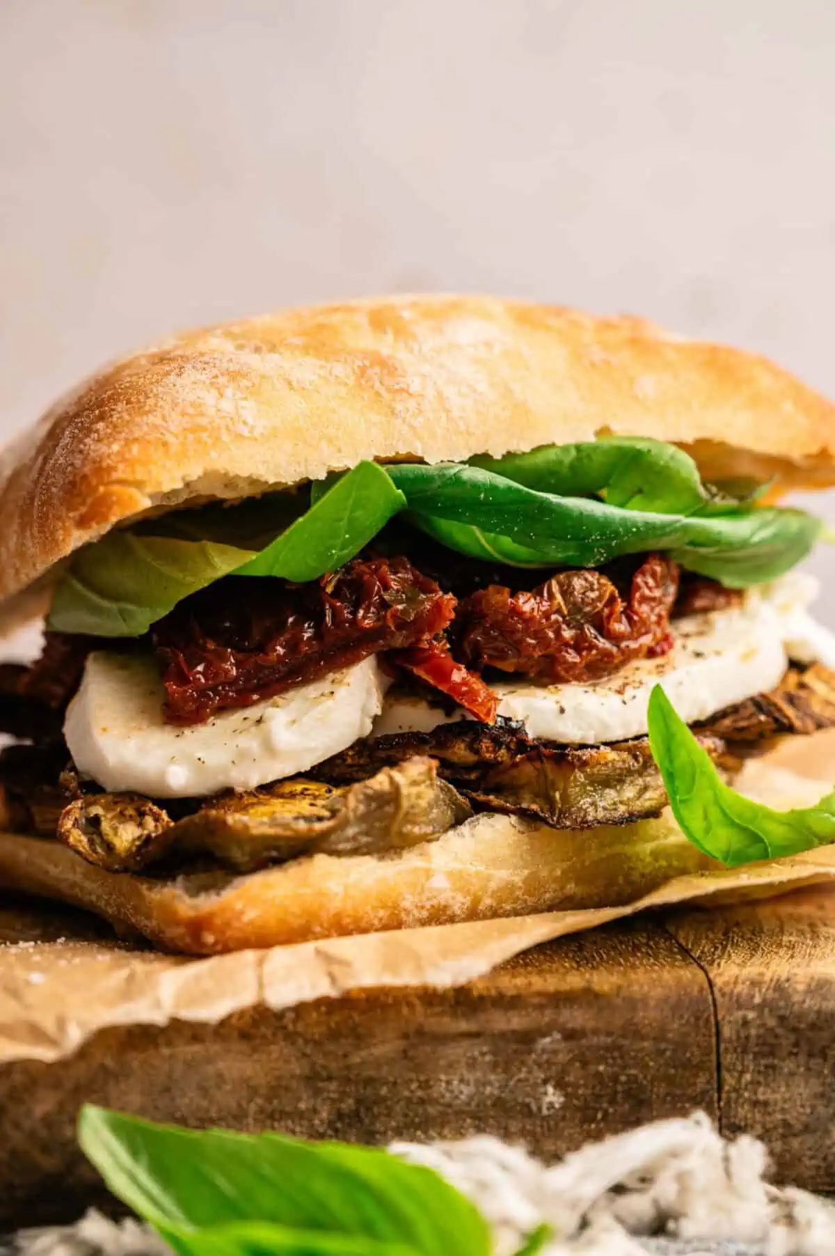 A roasted eggplant sandwich topped with fresh basil.