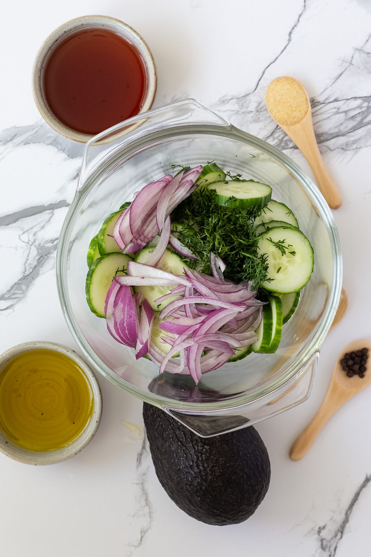 A bowl of sliced cucumbers with red onion and dill.