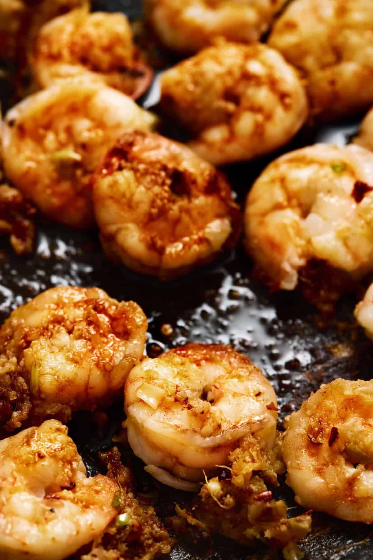A pan of cooked shrimp tossed with soy sauce.