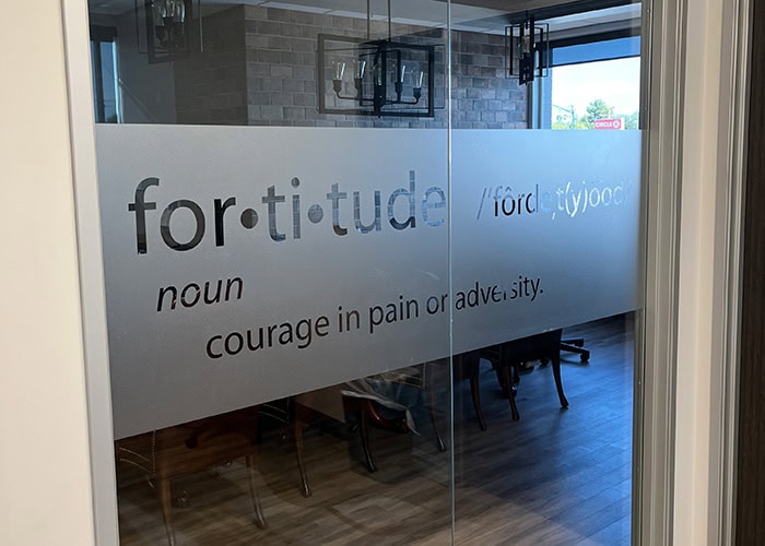 Fortitude Healthcare logo on glass door with definition of fortitude.