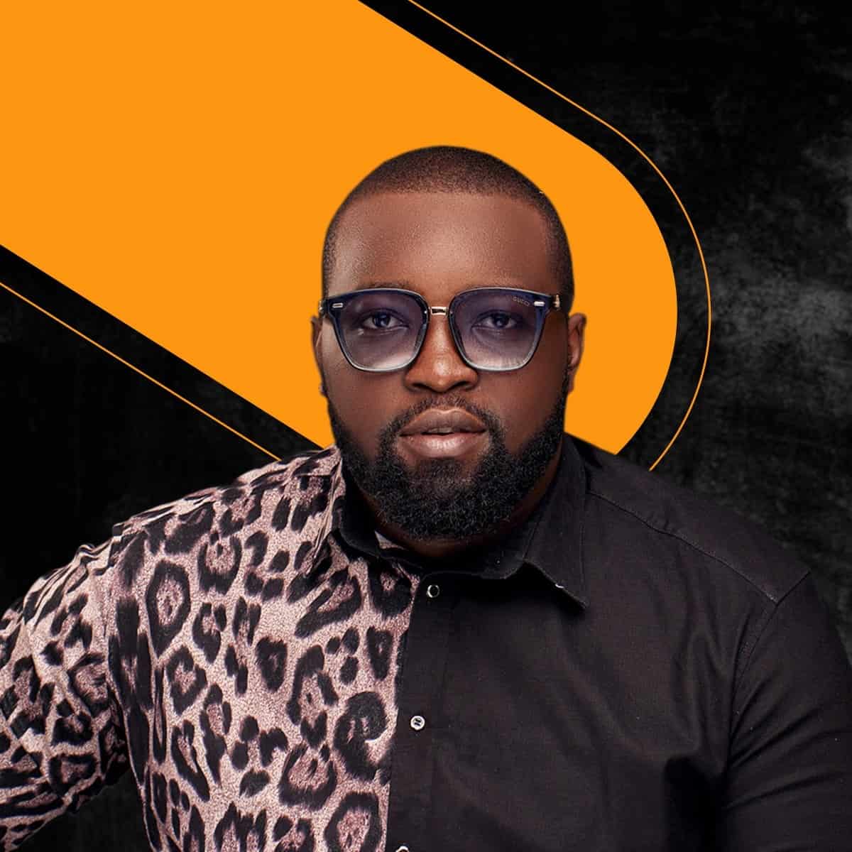 Man smiling warmly in a casual setting, wall background.