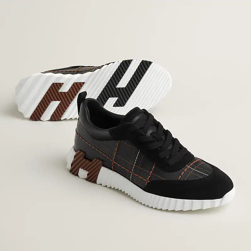 Stylish Hermès bouncing sneakers in black with orange stitching and white sole. Perfect for casual a.