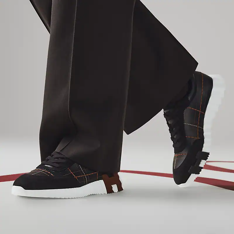 Bouncing Hermès sneakers in white with black and orange accents, stylish and modern footwear.