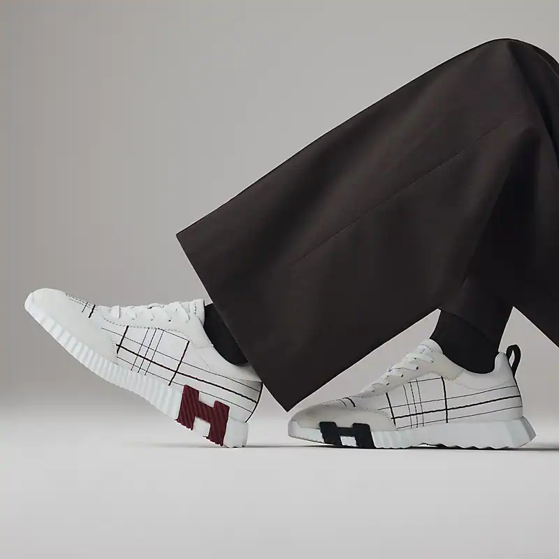 Hermès bouncing white sneakers with grid pattern and logo accents.